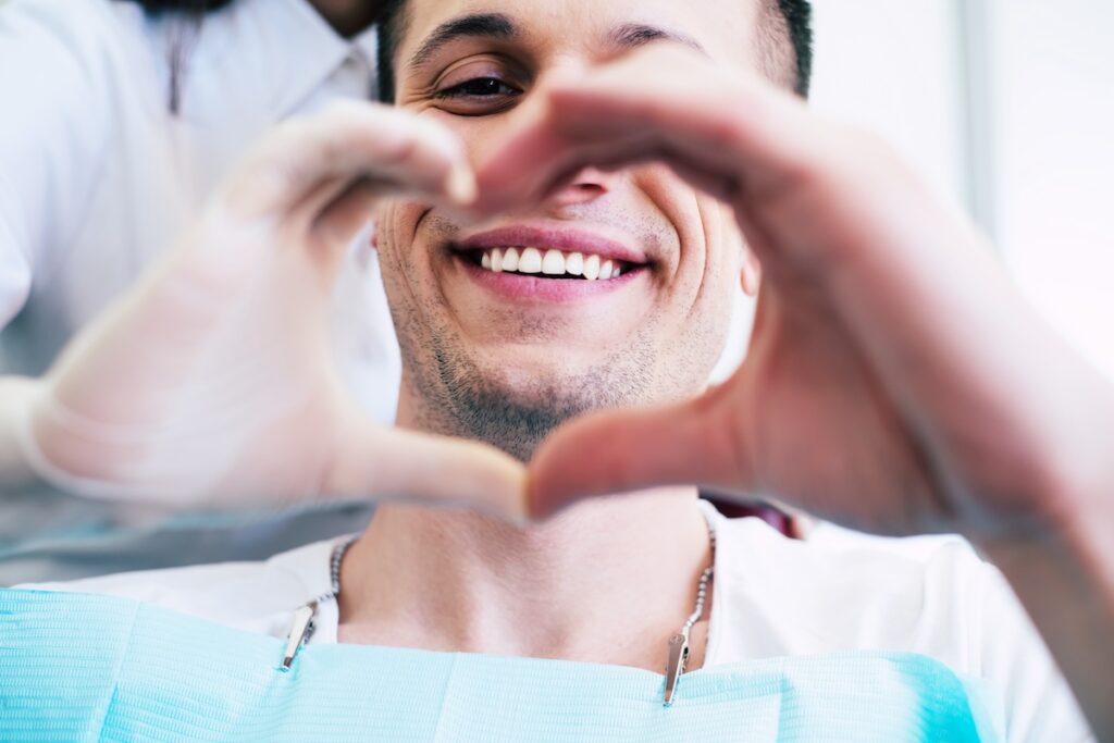 Man Smiling with a heart sign - Mid North Coast Dental